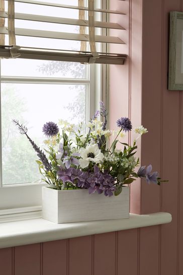 Flores artificiales de color púrpura lila en una caja de ventana