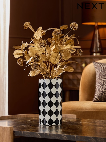 Arrangement af kunstigt løv i monokrom keramisk vase