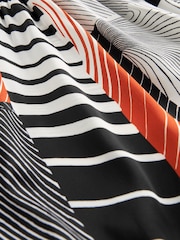 Monochrom/Orange mit abstraktem Print - Langärmliges Midikleid mit Bindeschleife - Bild 6 von 6