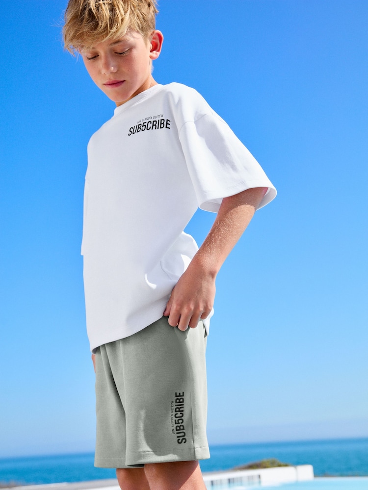 Weiß/Salbeigrün, Schriftzug - Set aus Kurzarm-T-Shirt und Shorts mit weiter Passform (3–16 Jahre) - Bild 1 von 10 Weiß/Salbeigrün, Schriftzug - Set aus Kurzarm-T-Shirt und Shorts mit weiter Passform (3–16 Jahre) - Bild 1 von 10