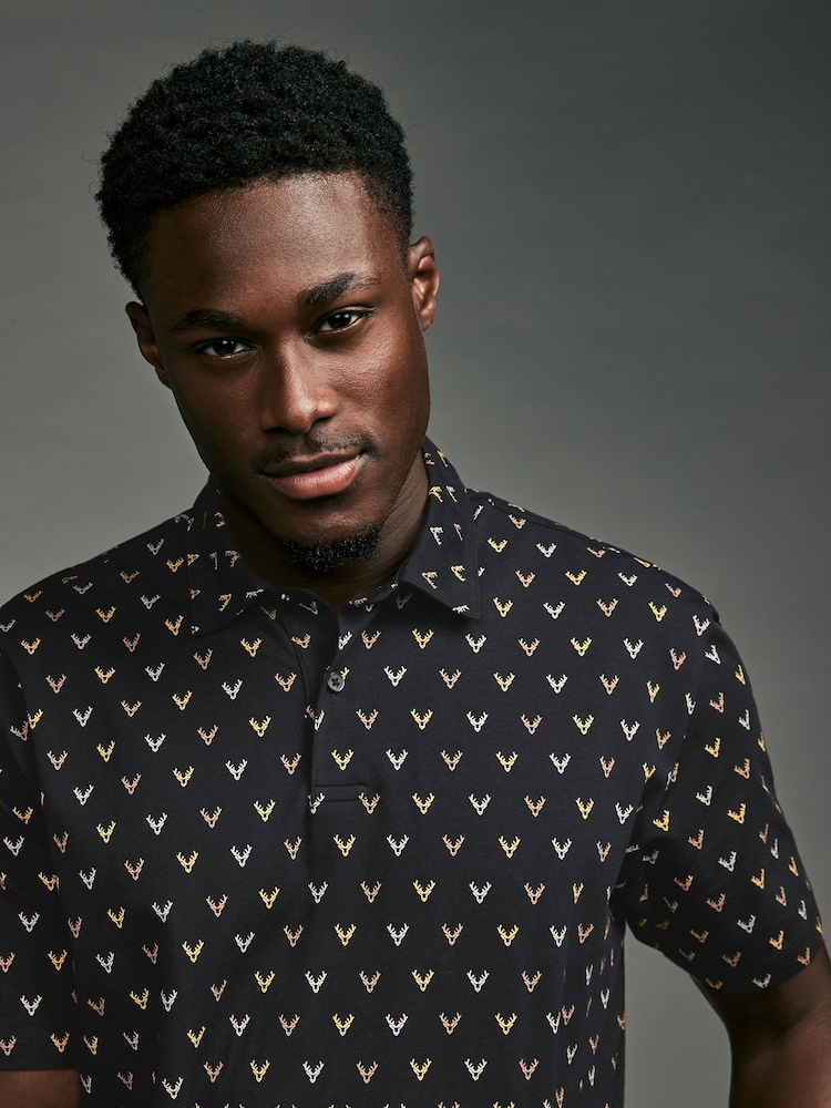Schwarz/Gold, Rentiermotiv - Polo-Shirt in weihnachtlichem Print - Bild 1 von 8 Schwarz/Gold, Rentiermotiv - Polo-Shirt in weihnachtlichem Print - Bild 1 von 8
