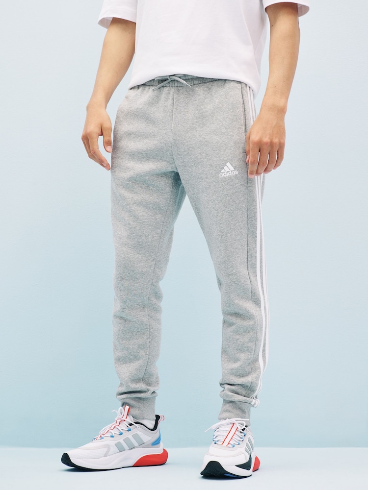 رمادي داكن - بنطلون رياضي 3 أشرطة من adidas Essentials - صورة 1 من 7 رمادي داكن - بنطلون رياضي 3 أشرطة من adidas Essentials - صورة 1 من 7