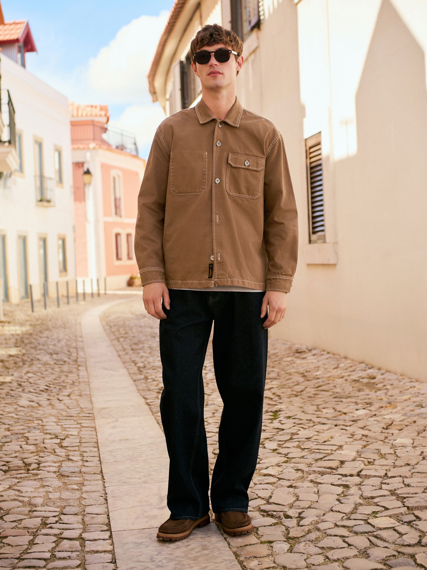 Brown canvas style shirt jacket with dark straight jeans and brown shoes