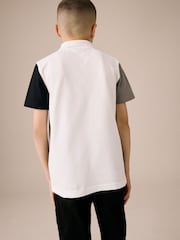 Weiß und Schwarz - Kurzarm-Polo-Shirt aus 100 % Baumwolle mit Viertelreißverschluss im Colourblock-Design (3–16 J.) - Bild 3 von 8