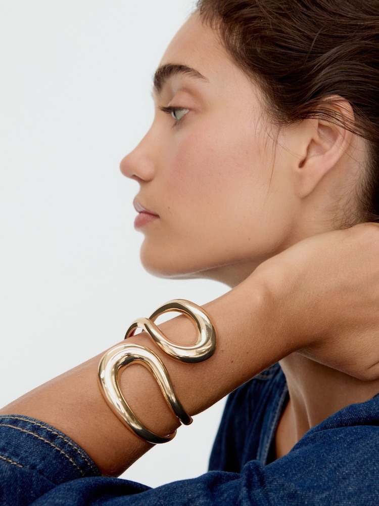 Oliver Bonas Gold Tone Remi Statement Looping Bangle - Image 1 of 5 Oliver Bonas Gold Tone Remi Statement Looping Bangle - Image 1 of 5