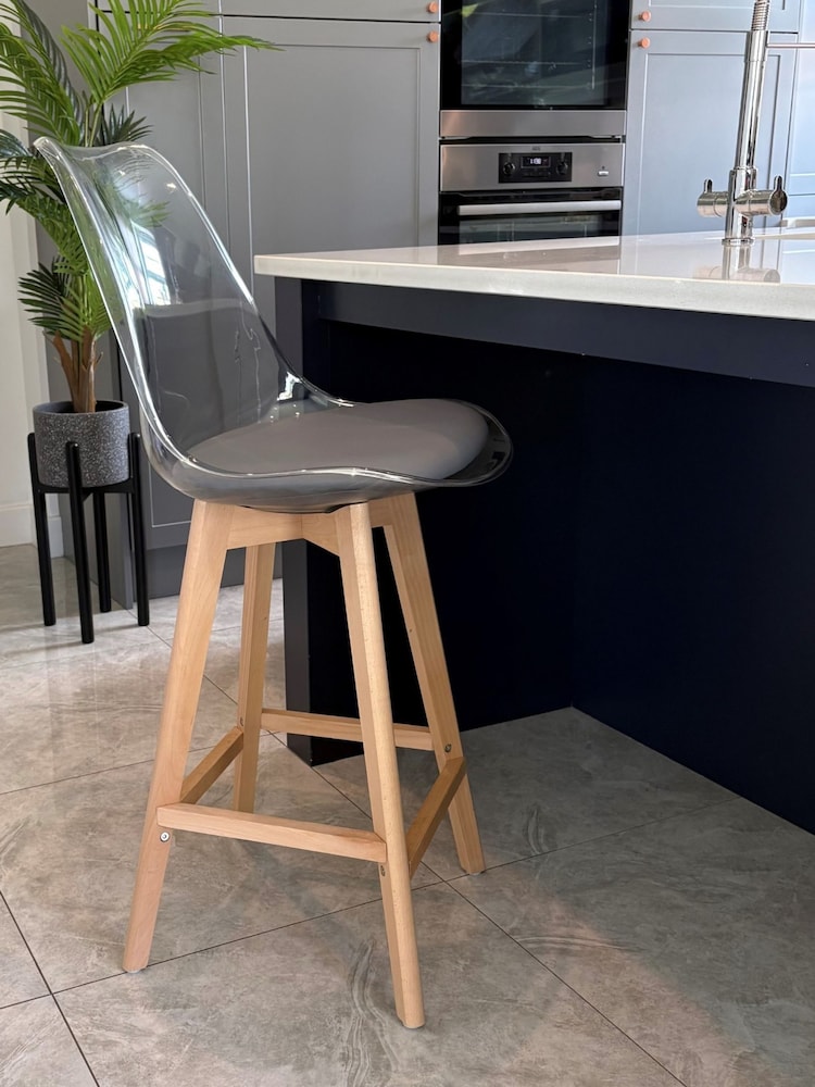Fusion Living Dark Grey Soho Clear Plastic Bar Stool with Light Wood Legs - Image 1 of 5 Fusion Living Dark Grey Soho Clear Plastic Bar Stool with Light Wood Legs - Image 1 of 5