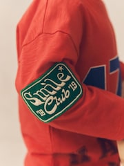 شارات ولون أحمر - تيشرت رياضي بكُم طويل مزيّن بطبعة فريق Varsity قطن 100% (3 أشهر - 7 سنوات) - صورة 2 من 5