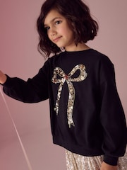 Black/Gold Sequin Bow Long Sleeve Wrap Back 100% Cotton Top (3-16yrs) - Image 1 of 4
