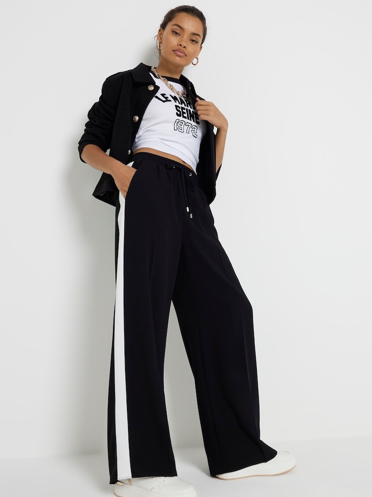 Черный - Широкие спортивные брюки с полосками по бокам River Island Petite - Изображение 1 из 8 Черный - Широкие спортивные брюки с полосками по бокам River Island Petite - Изображение 1 из 8