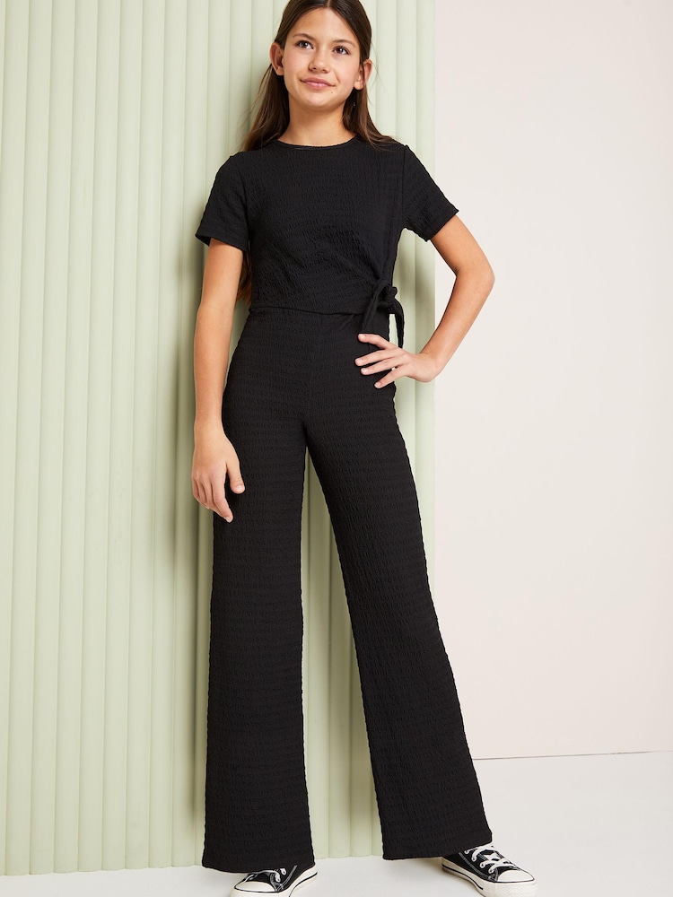 Lipsy Black Tie Side Crinkle Texture Jersey Jumpsuit (5-16yrs) - Image 1 of 2