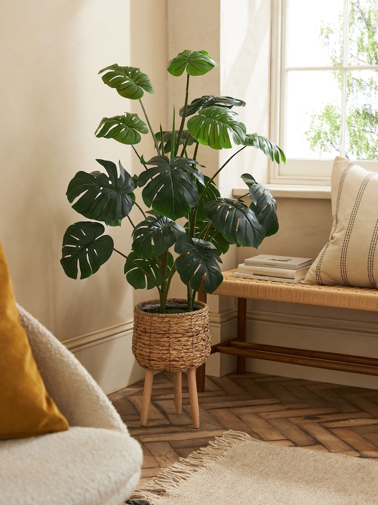Künstliches Arrangement aus Pflanzenblättern in Rattantopf mit Beinen - Bild 1 von 4 Künstliches Arrangement aus Pflanzenblättern in Rattantopf mit Beinen - Bild 1 von 4
