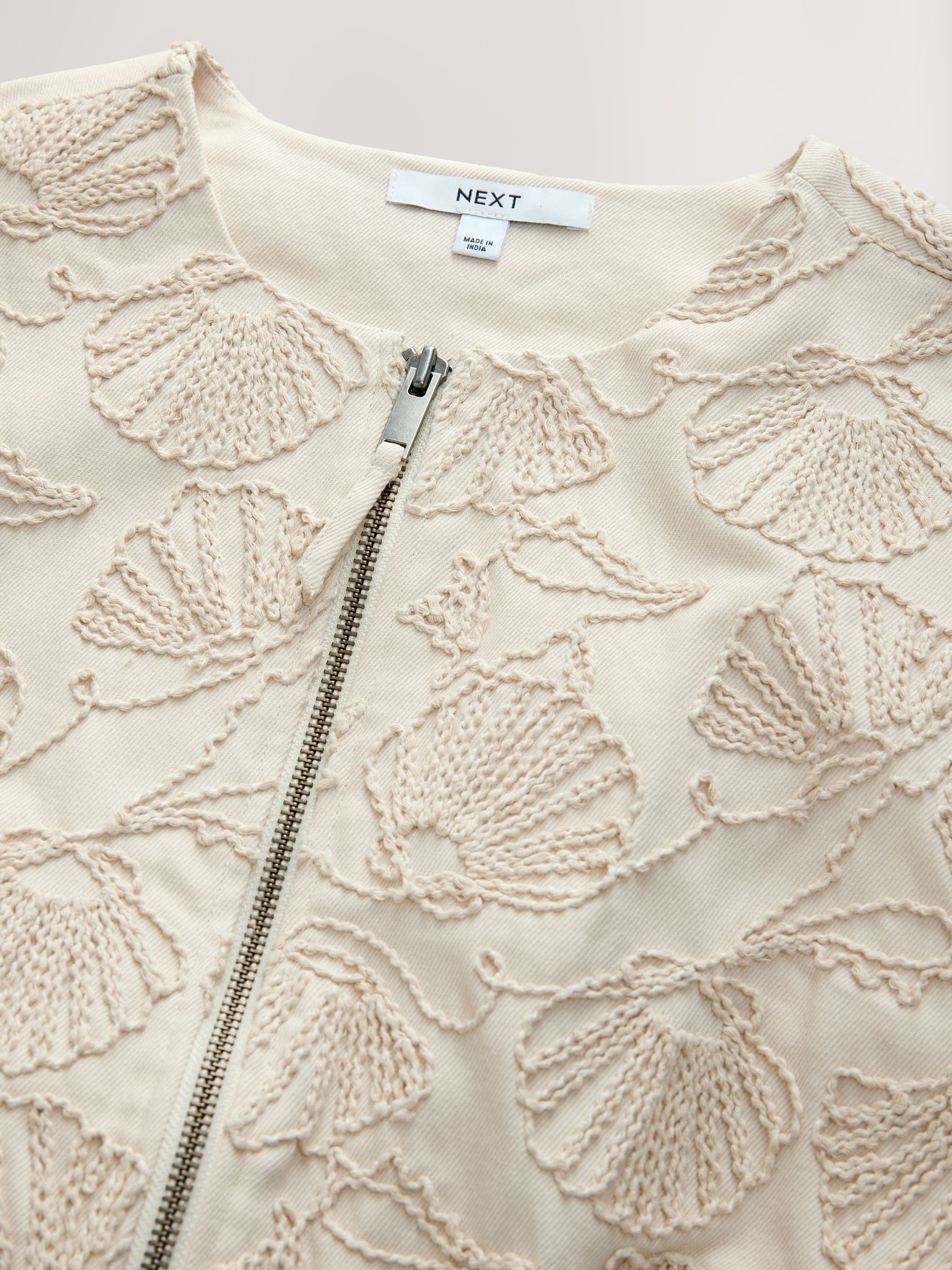 Next：日本 ベージュ - Seashell 刺繍入りコットンジップアップ